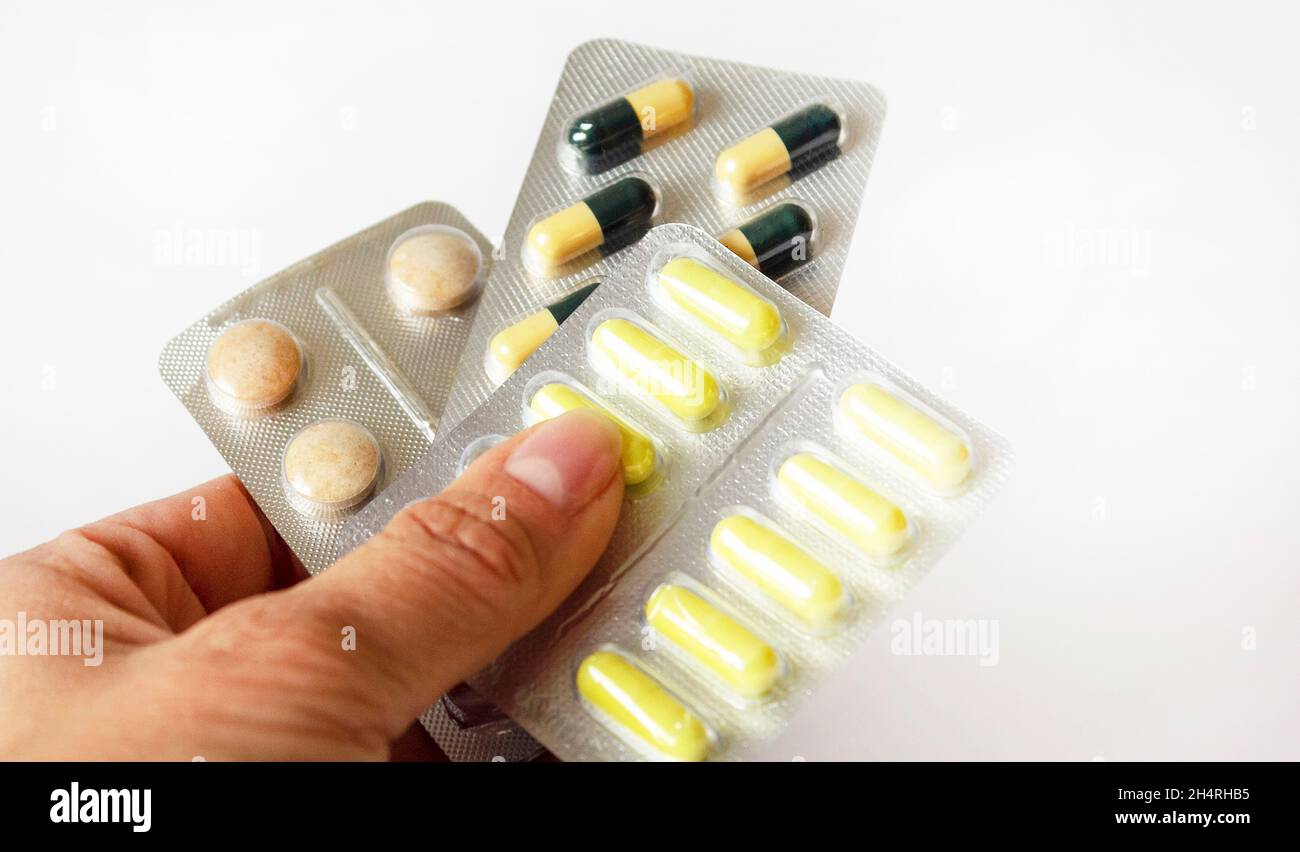 Donna che tiene pillole in blister su sfondo bianco, primo piano Foto Stock