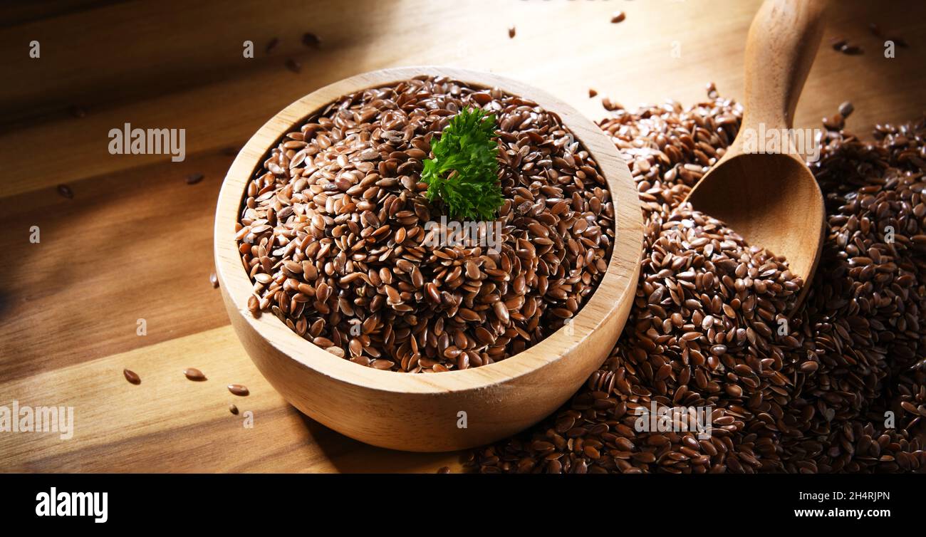 Ciotola di semi di lino marrone su tavola di legno. Foto Stock