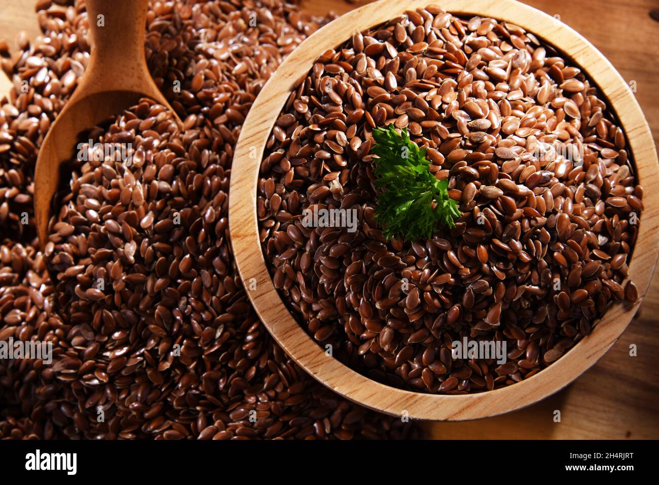 Ciotola di semi di lino marrone su tavola di legno. Foto Stock