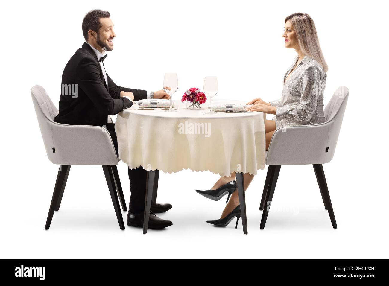 Giovane ed elegante uomo e donna seduti ad un tavolo da ristorante isolato su sfondo bianco Foto Stock