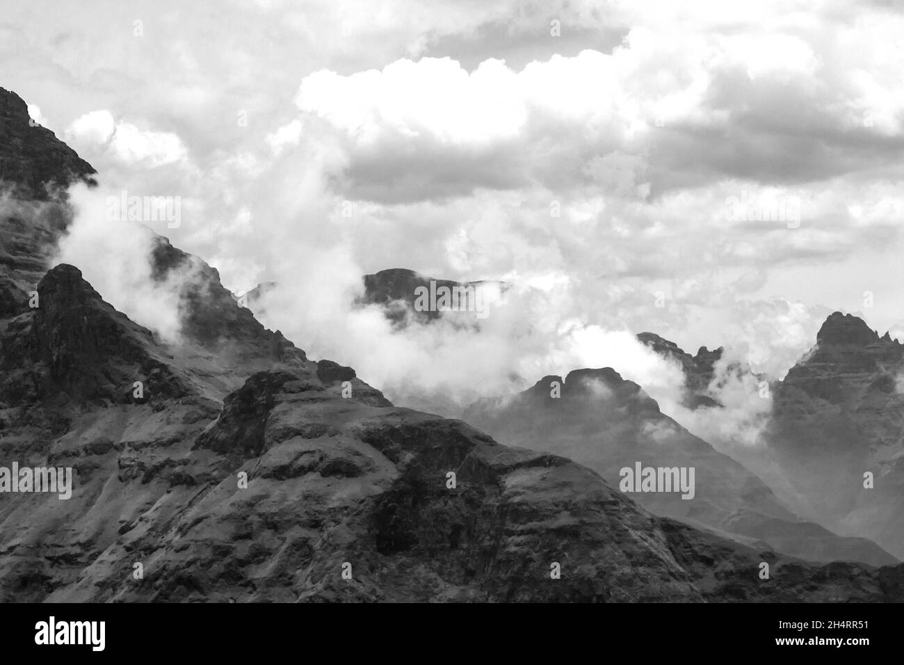 Nuvole che si raccolgono tra le alte cime frastagliate dei Monti Drakensberg, parte della grande scarpata del Sudafrica, in bianco e nero. Foto Stock