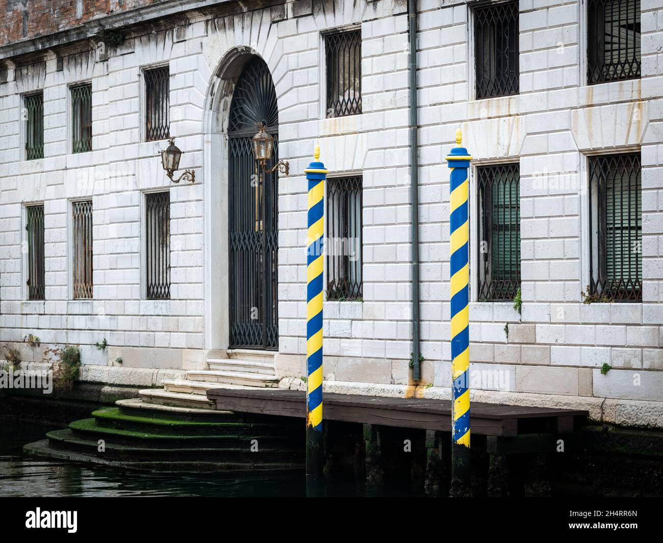 Pali gialli a strisce blu di fronte alla vecchia casa di Venezia (Italia) Foto Stock