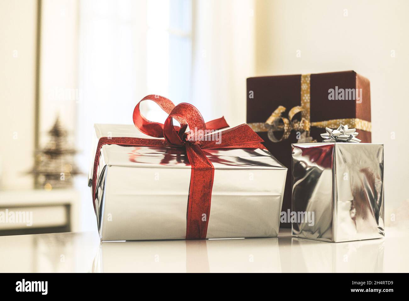 Scatole regalo vicino albero di Natale dentro casa. Scatola con nastro per  vacanze con archi. Calda atmosfera festosa per famiglie, al coperto. Anno  nuovo, felicità, togetherne Foto stock - Alamy