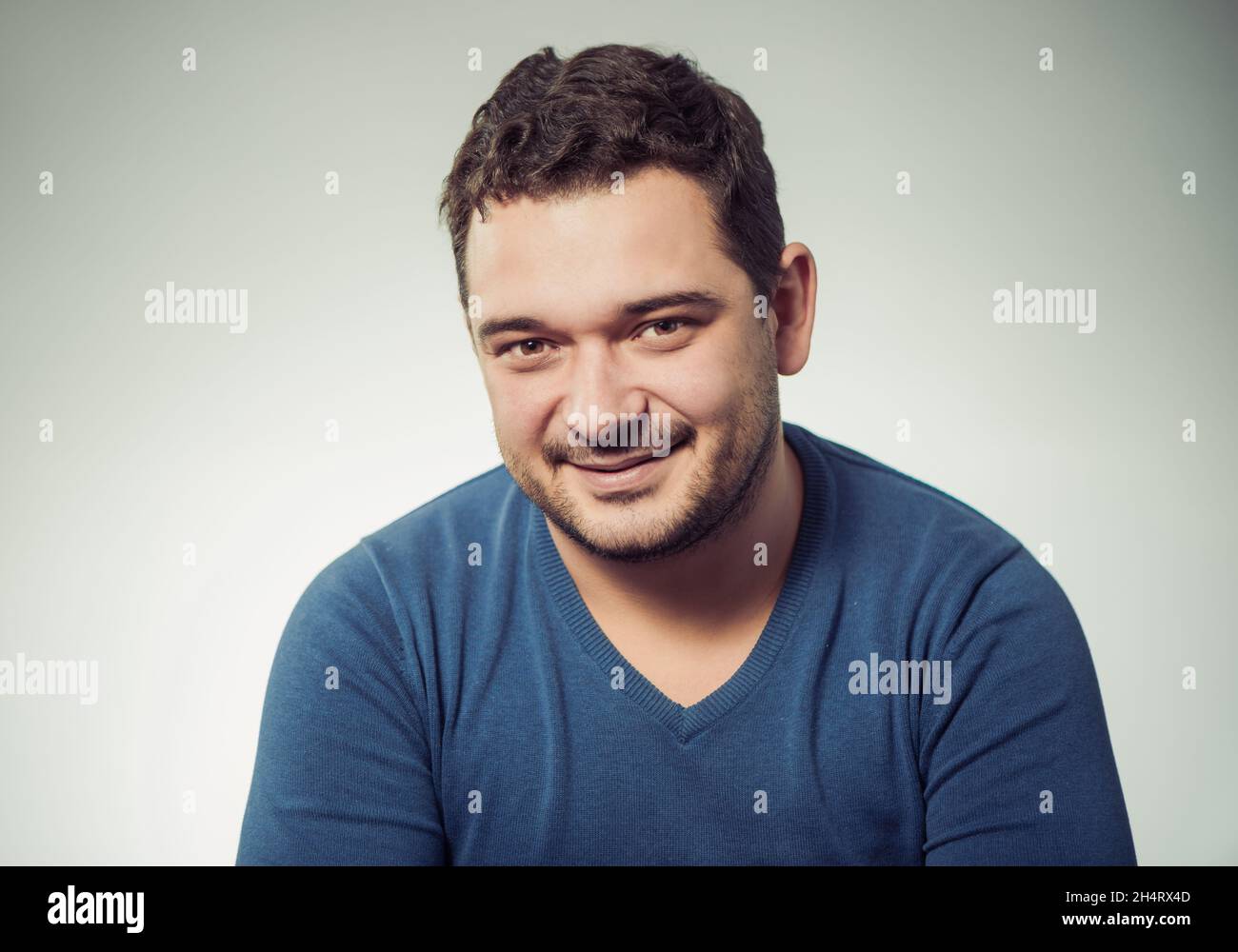 giovane ritratto positivo uomo in maglione blu sullo sfondo dello studio Foto Stock