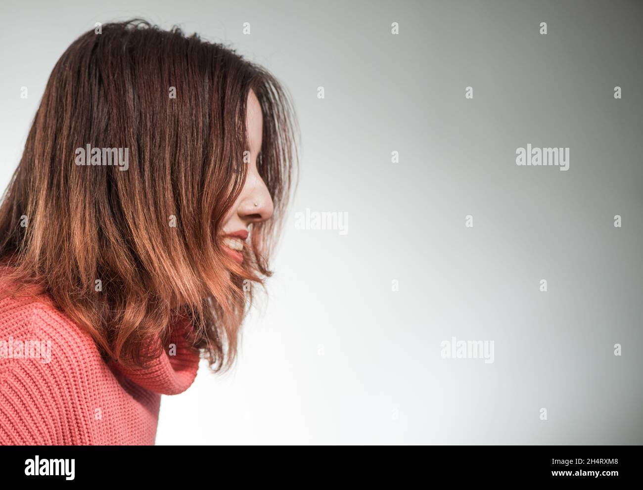 giovane donna timida ritratto in maglione rosa su sfondo studio Foto Stock
