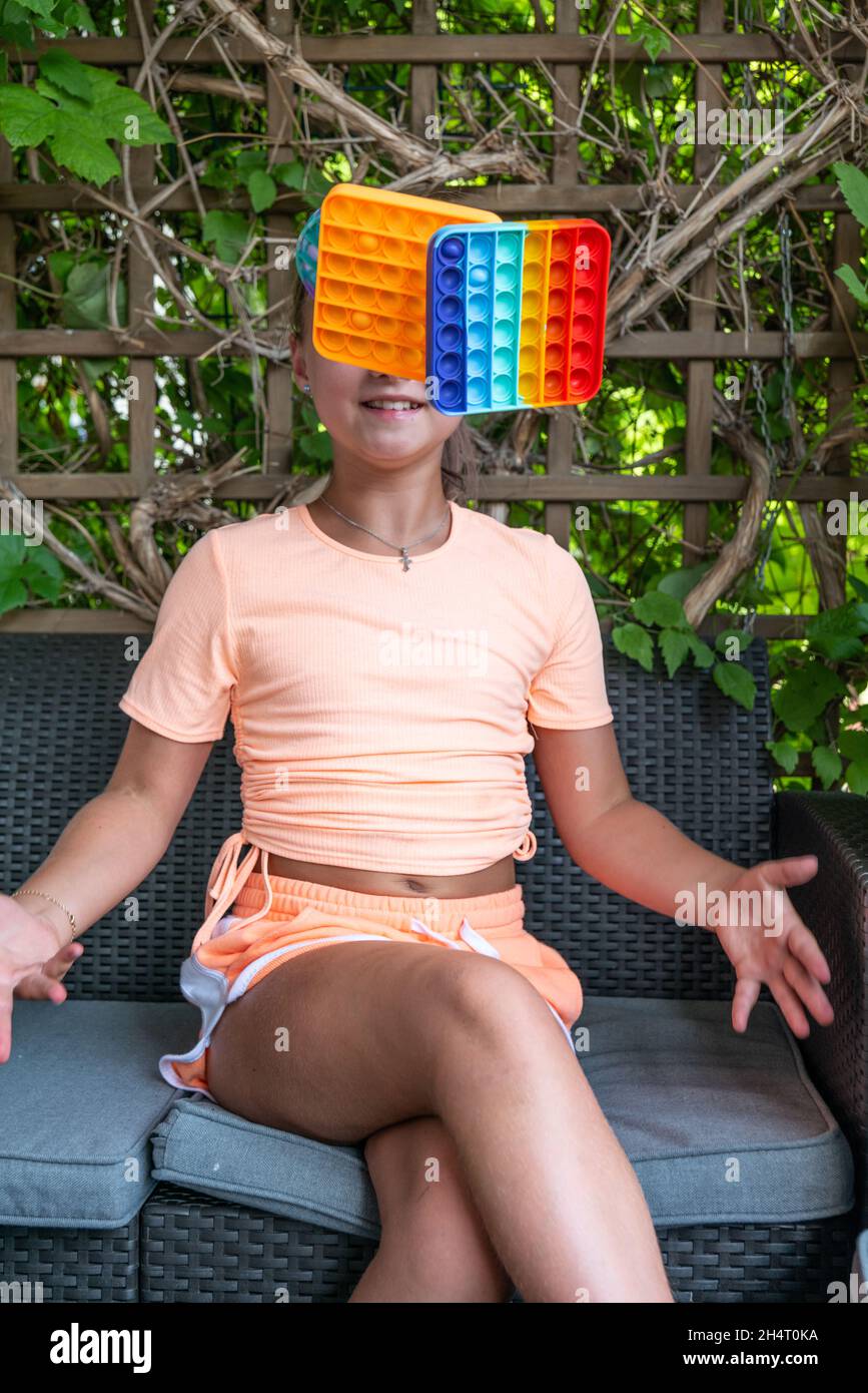 Ragazza con Pop IT giocattolo o gioco da tavolo giocare all'aperto, sviluppo di abilità motorie, premendo le bolle con le dita, antistress giocattolo pop trendy. Concente Foto Stock
