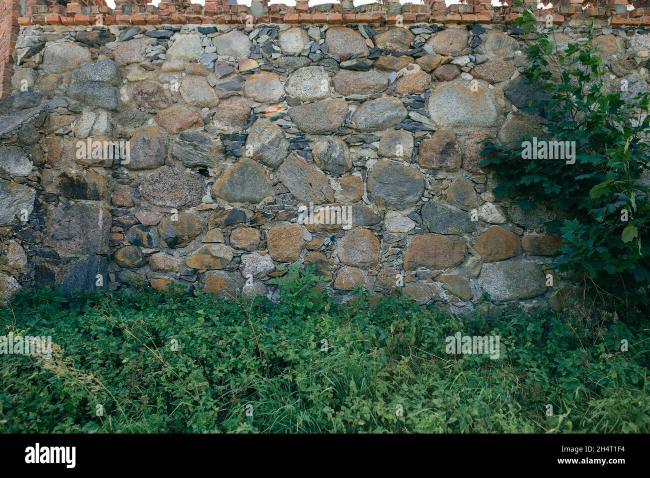 alto muro del castello fatto di grande pietra intervallata da piccolo pietre Foto Stock