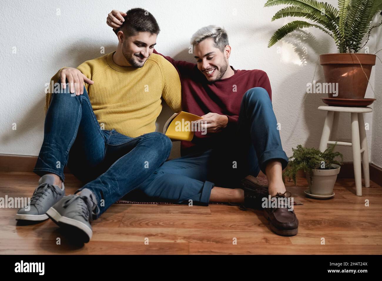 Gay uomo coppia lettura libro insieme indoor in casa - LGBT omosessuale amore momenti concetto Foto Stock