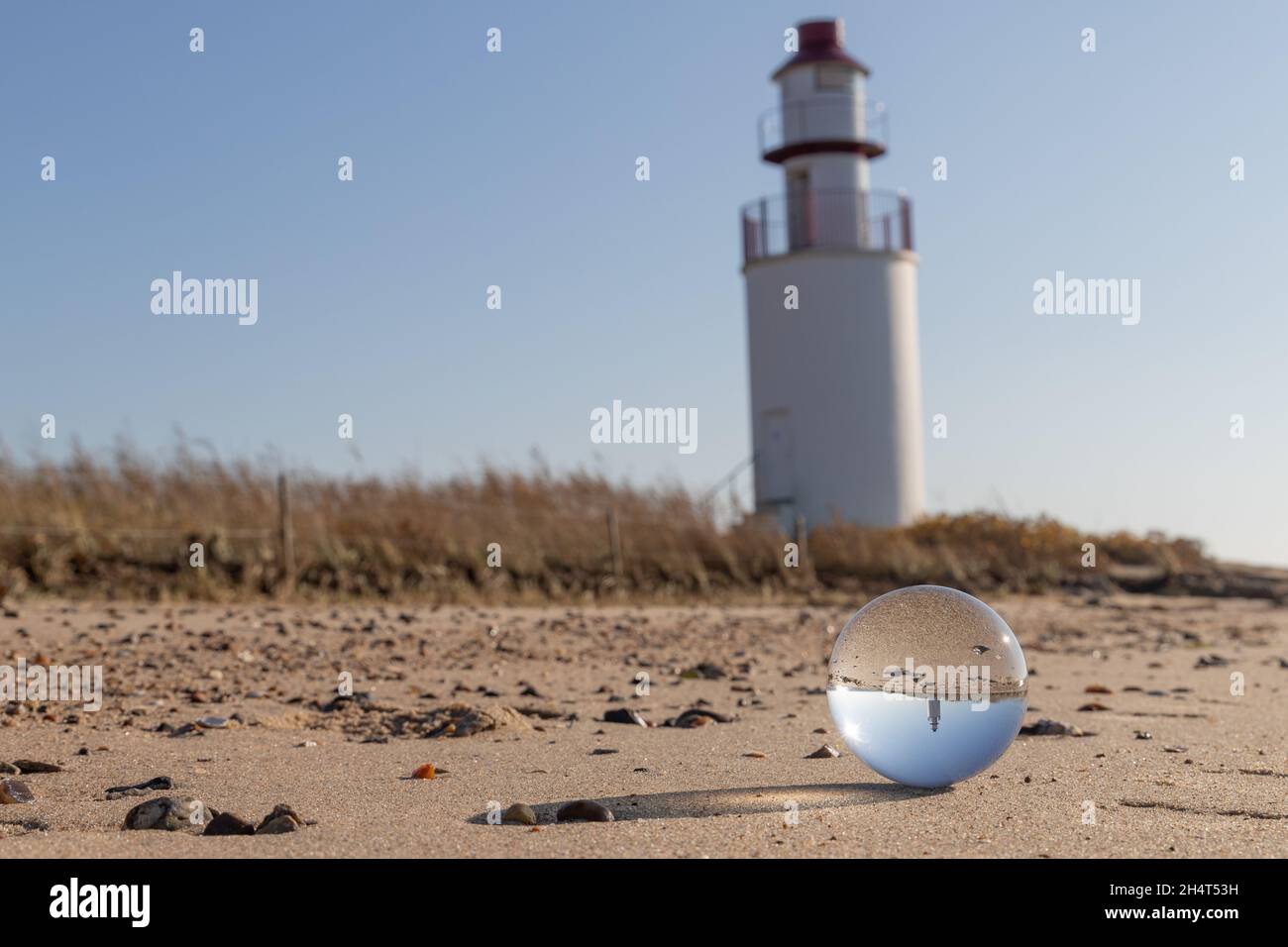 Stouby, Danimarca - 29 ottobre 2021: Faro di Traeskohage bianco sul lato settentrionale del fiordo di Vejle con una palla da lensball in primo piano Foto Stock