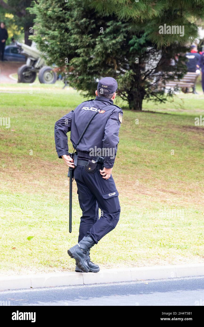Huelva, Spagna - 30 ottobre 2021: Vista posteriore della polizia nazionale spagnola con il logo 'Policia' emblema su uniforme, mantenere l'ordine pubblico per le strade o Foto Stock