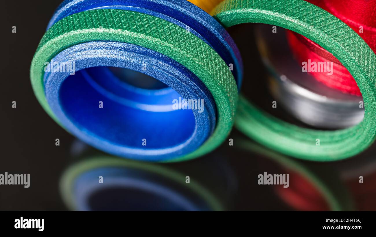 I dadi zigrinati verdi e le boccole di guida del router colorate sono dettagli su uno sfondo nero con un bel riflesso. Primo piano degli anelli in alluminio anodizzato. Foto Stock