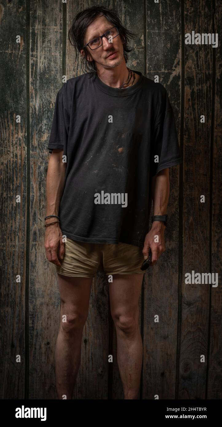 Uomo capelli neri con pantaloncini verdi dell'esercito vicino alla vecchia parete di legno Foto Stock