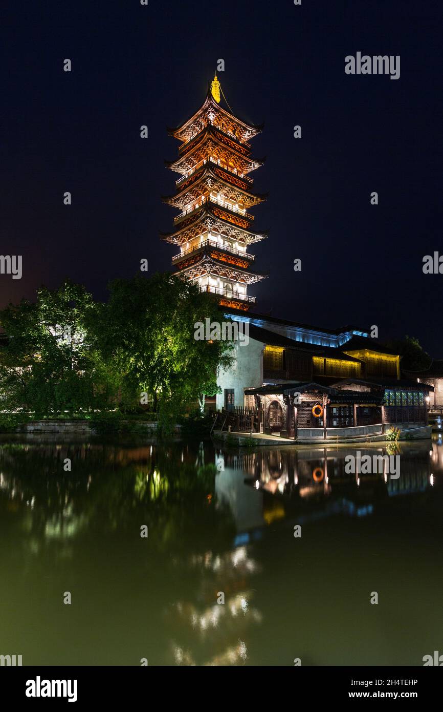 La Pagoda del Loto Bianco o Pagoda Ovest si illuminano di notte nella città d'acqua di Wuzhen, Cina. Foto Stock