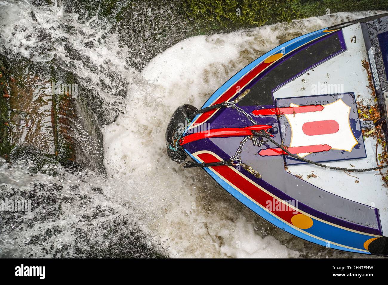 Vista dall'alto dell'estremità anteriore di un narrowboat isolato all'interno di una serratura del canale del Regno Unito mentre si riempie d'acqua. Foto Stock