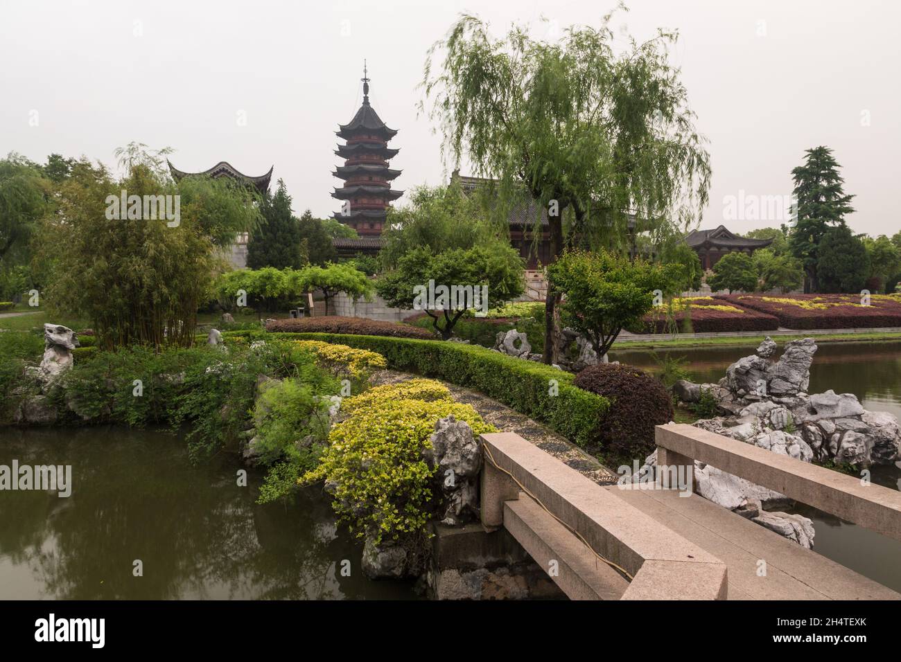 Un ponte nei giardini della Pan Gate Scenic Area con la Pagoda Ruiguang alle spalle. Suzhou, Cina. Foto Stock