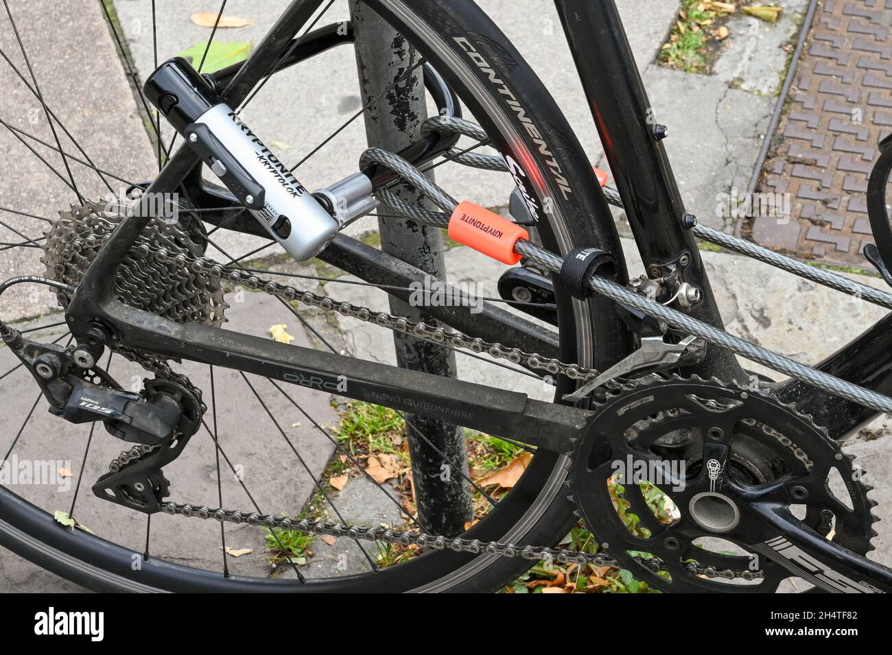 Bath, Inghilterra - Agosto 2021: Primo piano di un cavo in acciaio e serratura che fissa un telaio per bicicletta ad un portabiciclette Foto Stock