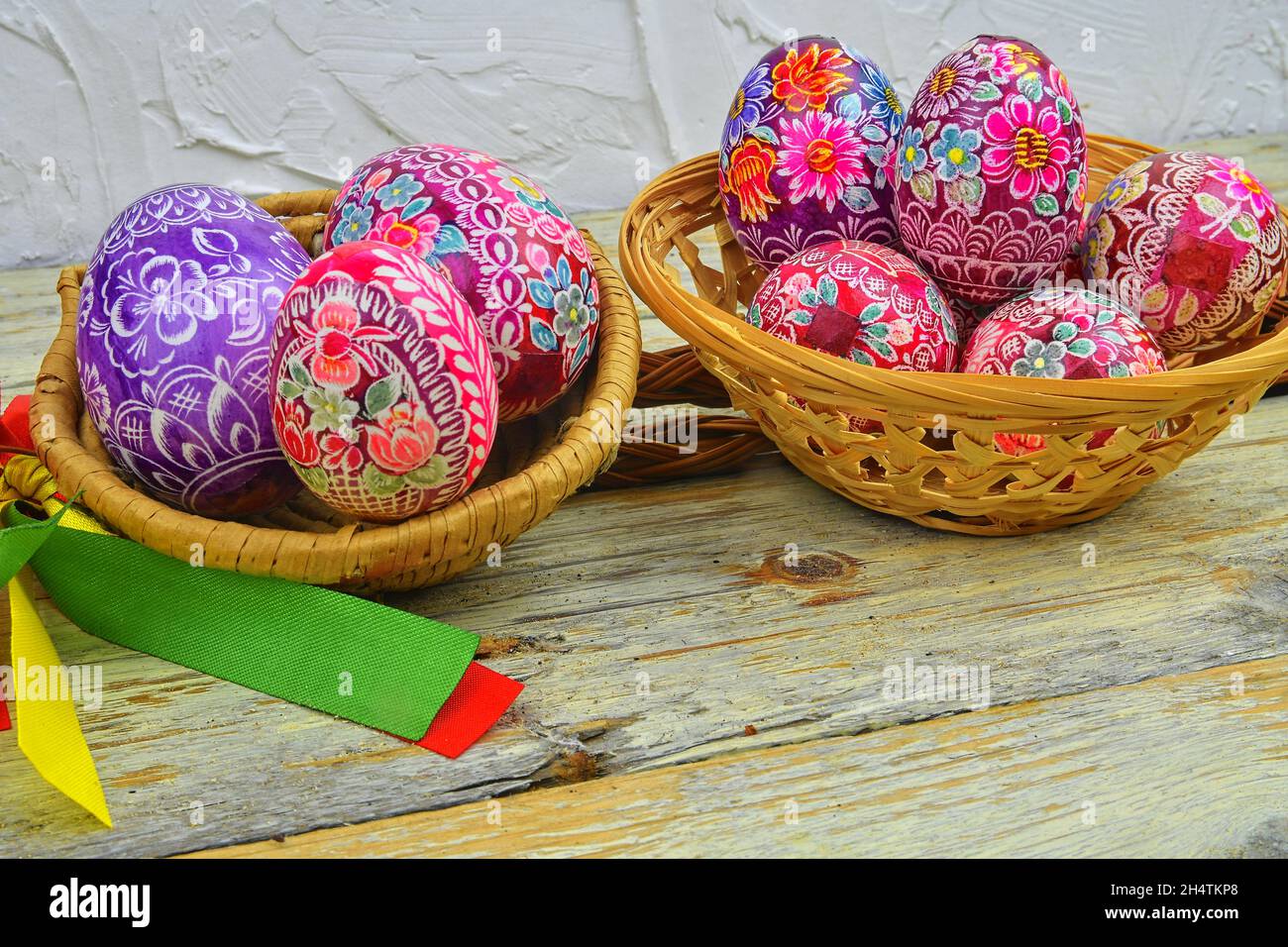 Ancora la vita con le uova di Pasqua. Le uova di Pasqua decorate si depongono in un cesto di vimini su uno sfondo di legno bianco. Uova di Pasqua, decorate con folk tradizionale Foto Stock