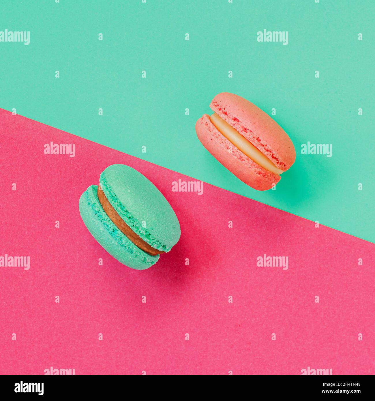 Due macaron francesi su sfondo vivace e colorato, dessert parigino, cibo dolce. Disposizione piatta Foto Stock