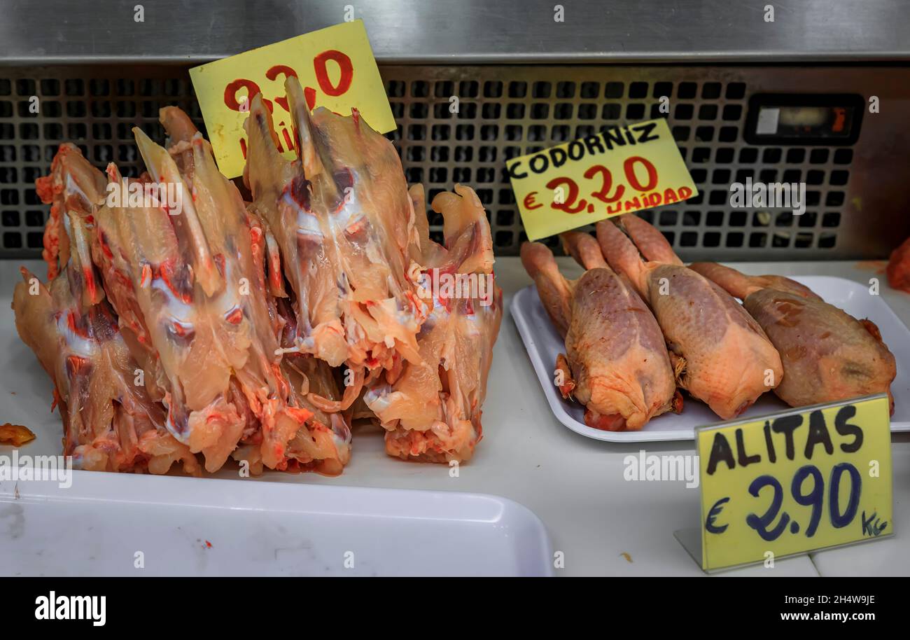 Quaglia cruda intera e carcassa di pollo in vendita presso un macellaio locale, con le relative etichette di prezzo, nel centro storico o casco Viejo di Pamplona, Spagna Foto Stock
