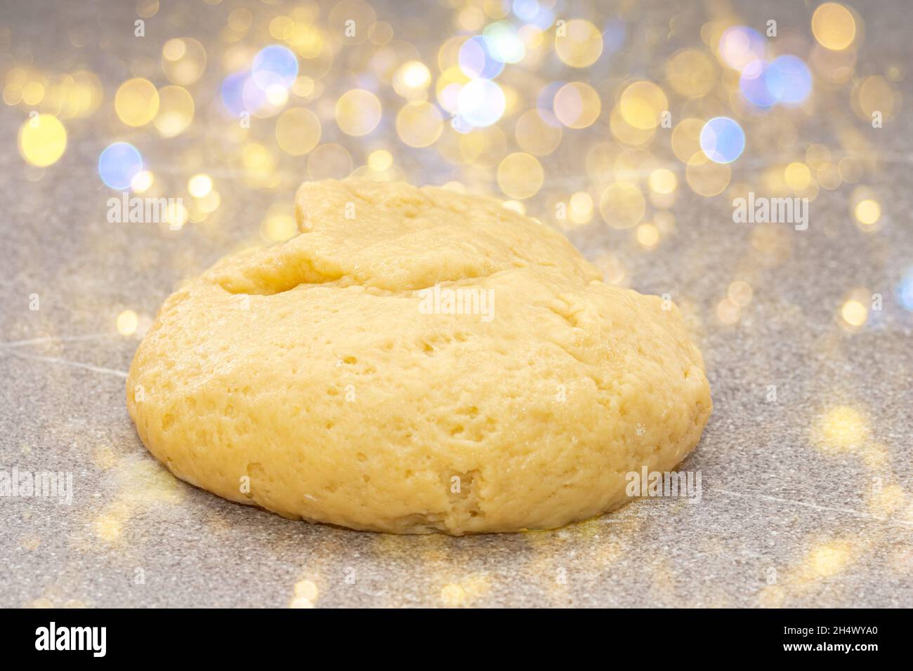 Pasta fresca gialla cruda a forma di palla per la cottura degli uomini di pan di zenzero per Natale su uno sfondo favoloso con bokeh giallo. Cibo di Natale trad Foto Stock