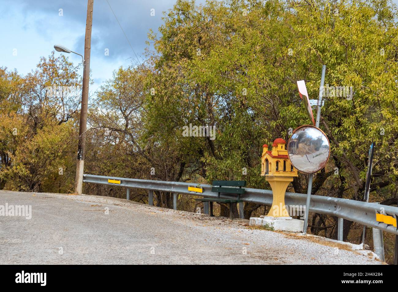 Santuario della strada, cappella commemorativa in Grecia su strada di montagna pericolosa svolta con installato specchio sul lato della strada. Lontano villaggio su Lefkada i Foto Stock