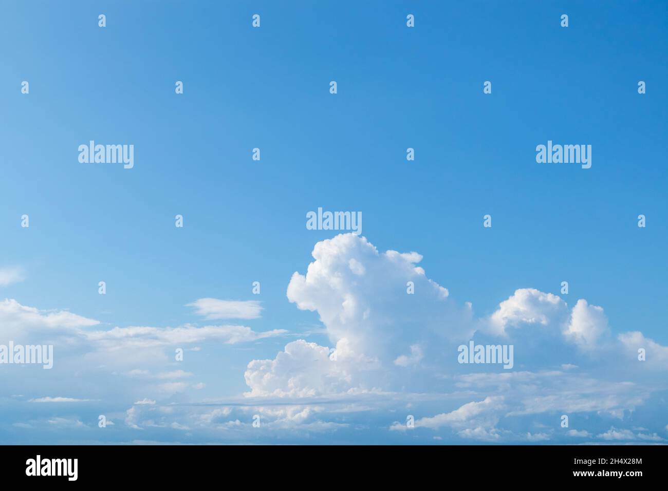 Soffice nuvole bianche alte su cielo azzurro brillante, sfondo nuvoloso. Paesaggio naturale paradisiaco in estate sopra il mare Foto Stock