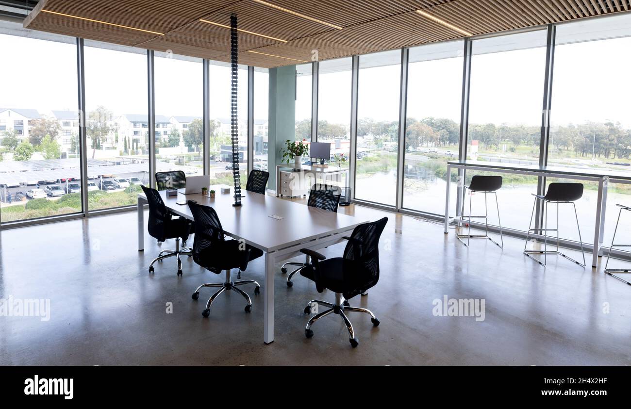 Sedie girevoli nere vuote disposte intorno alla scrivania in un ufficio moderno Foto Stock
