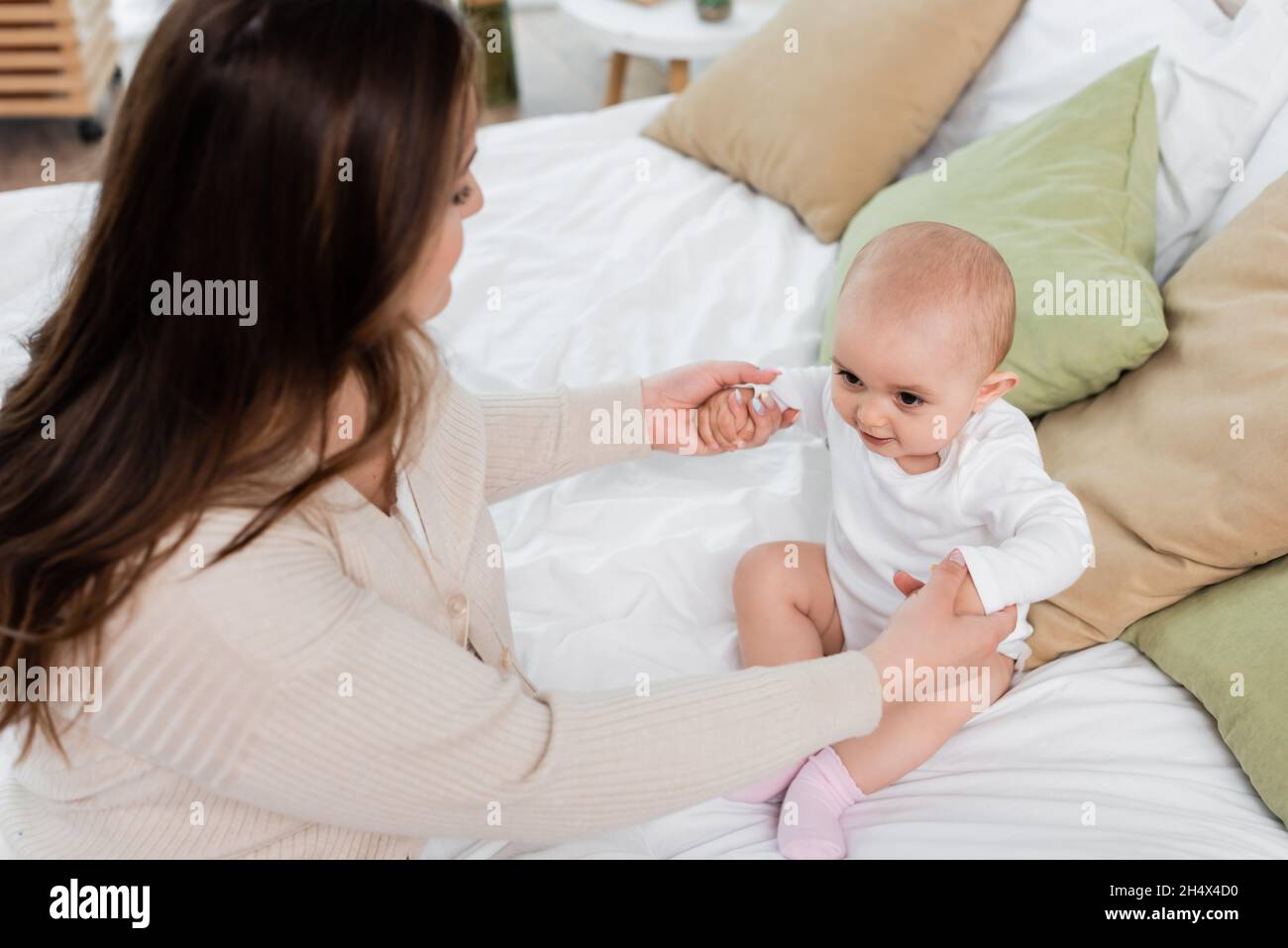 Vista ad angolo alto della madre che tiene le mani della figlia del bambino sul letto Foto Stock