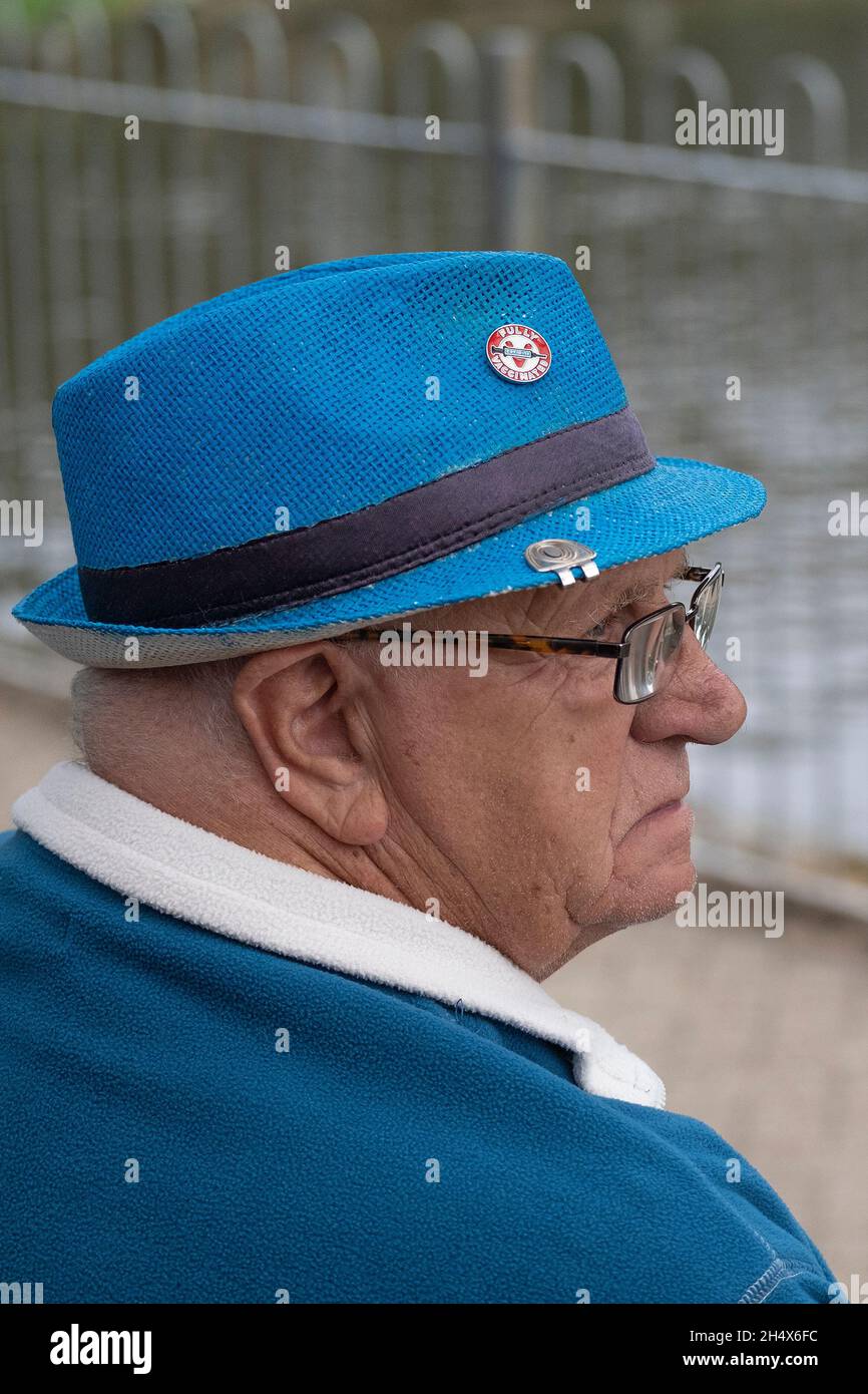Uomo maturo che indossa un pile blu e un cappello blu con un distintivo completamente vaccinato. Foto Stock