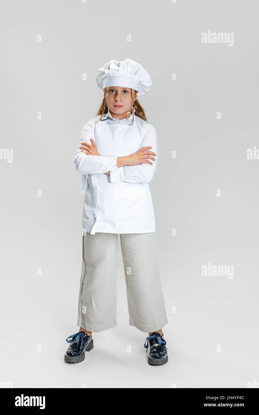 Donna che indossa un cappello chef in piedi con le braccia incrociate  tenendo una siviera Foto stock - Alamy
