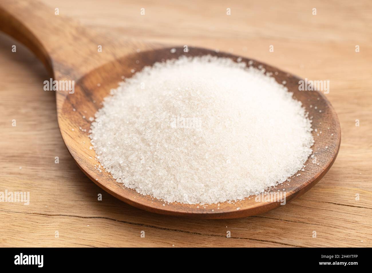 Zucchero in cucchiaino di legno su tavola di legno. Primo piano Foto Stock