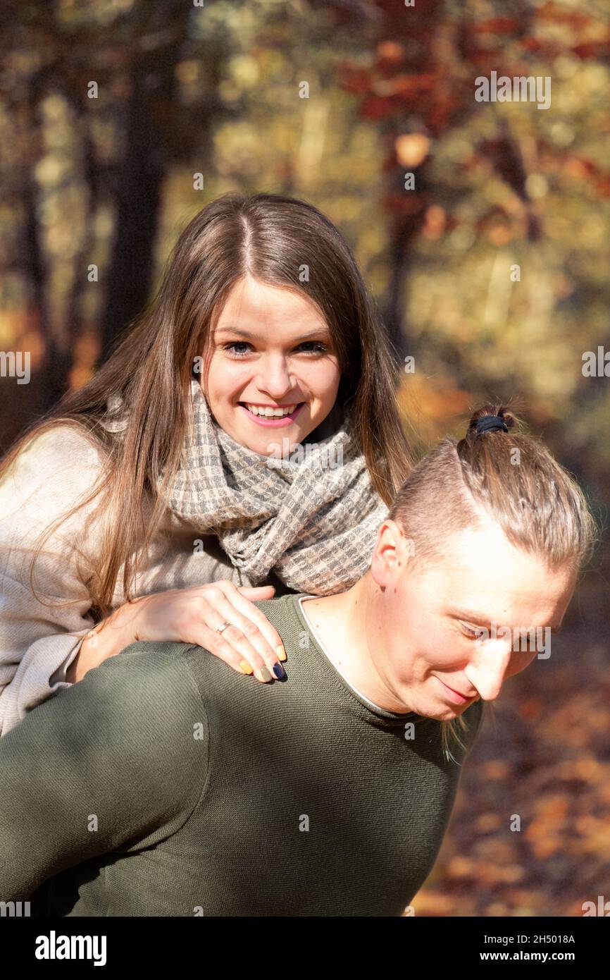 Rapporto, stile di vita e concetto di stagioni. Giovane e attraente coppia divertirsi nel parco durante la soleggiata giornata autunnale. Filtro colore vintage con applicazione grana Foto Stock