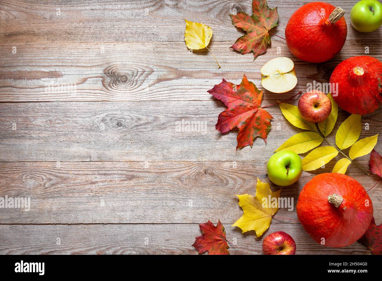 Il confine autunnale da mele, zucca e foglie cadute su un vecchio tavolo di legno. Concetto di giorno di ringraziamento. Zucca di ringraziamento con frutta. Frutta e vegeto Foto Stock