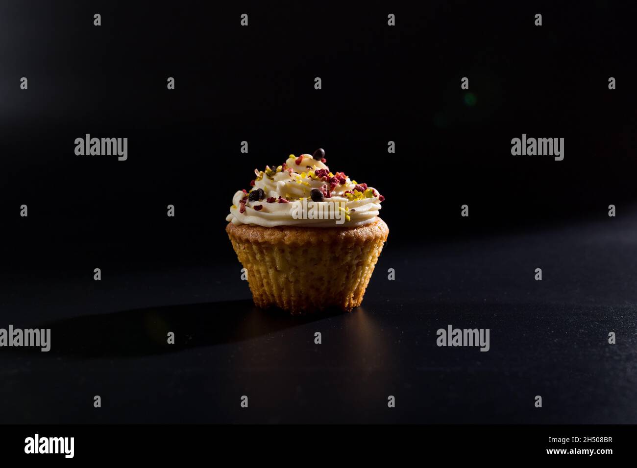 Una bella torta di tazza da vicino su sfondo nero con crema sulla parte superiore. Foto Stock