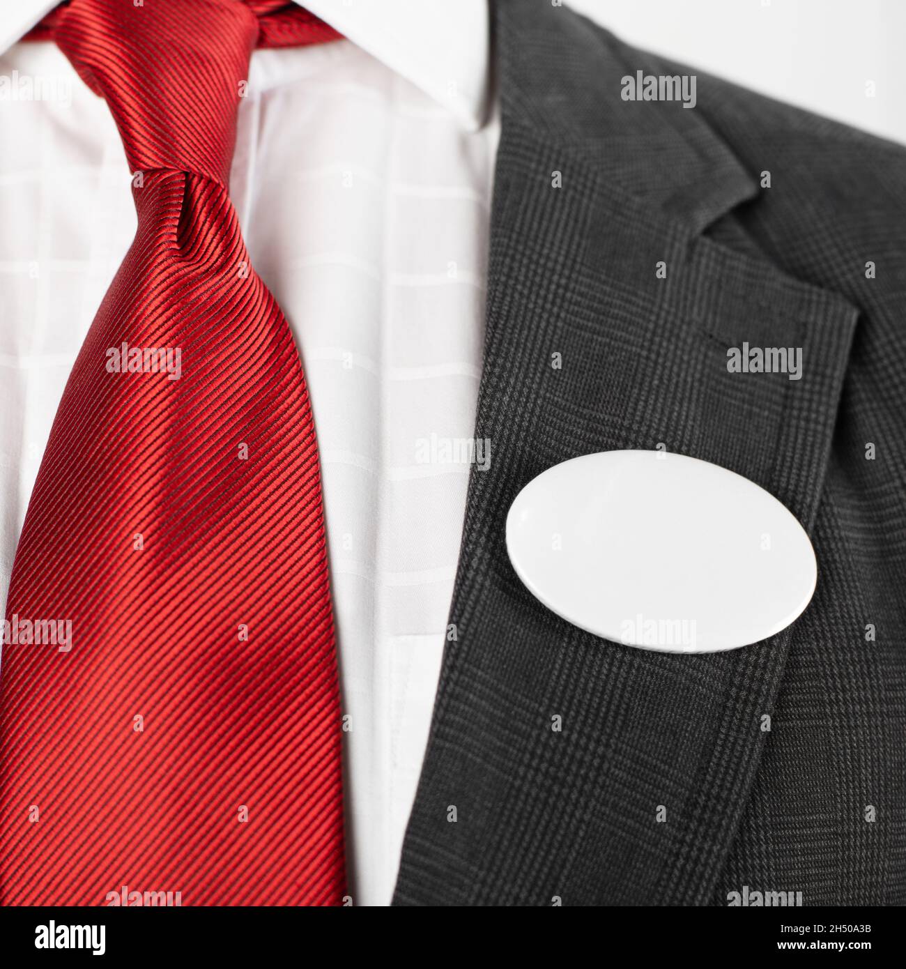 Bottone ovale bianco vuoto con spazio copia fissato al vestito da uomo Foto Stock
