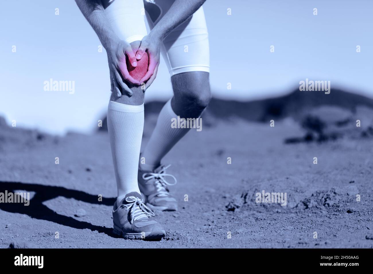 Ginocchio dolore atleta sport ferita uomo runner in esecuzione su pista gara con sport problema di salute tenuta dolorosa gamba. La lacerazione del legamento ACL è una delle più importanti Foto Stock
