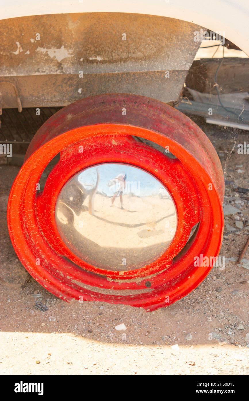mozzo ruota cromato e rosso sul relitto dell'auto in un cortile desertico Foto Stock