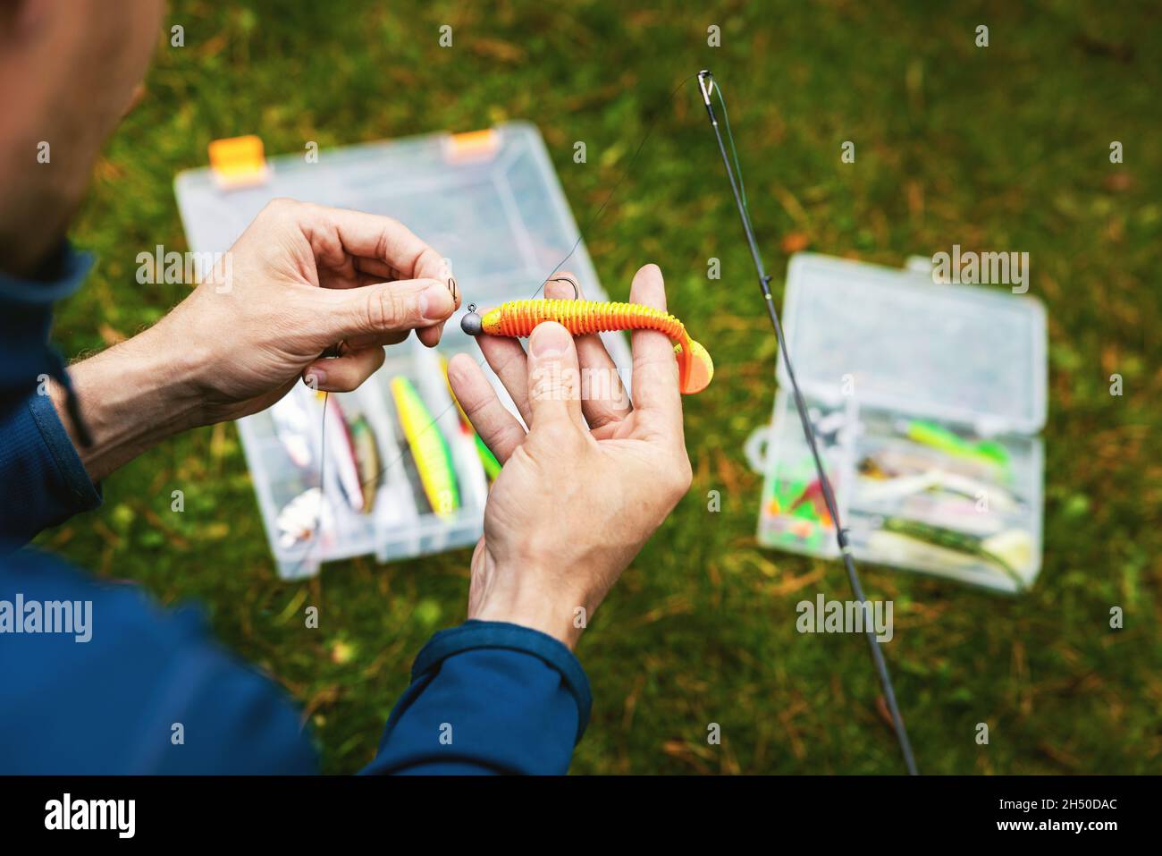 pescatore che mette su esca di plastica morbida di pesca Foto Stock