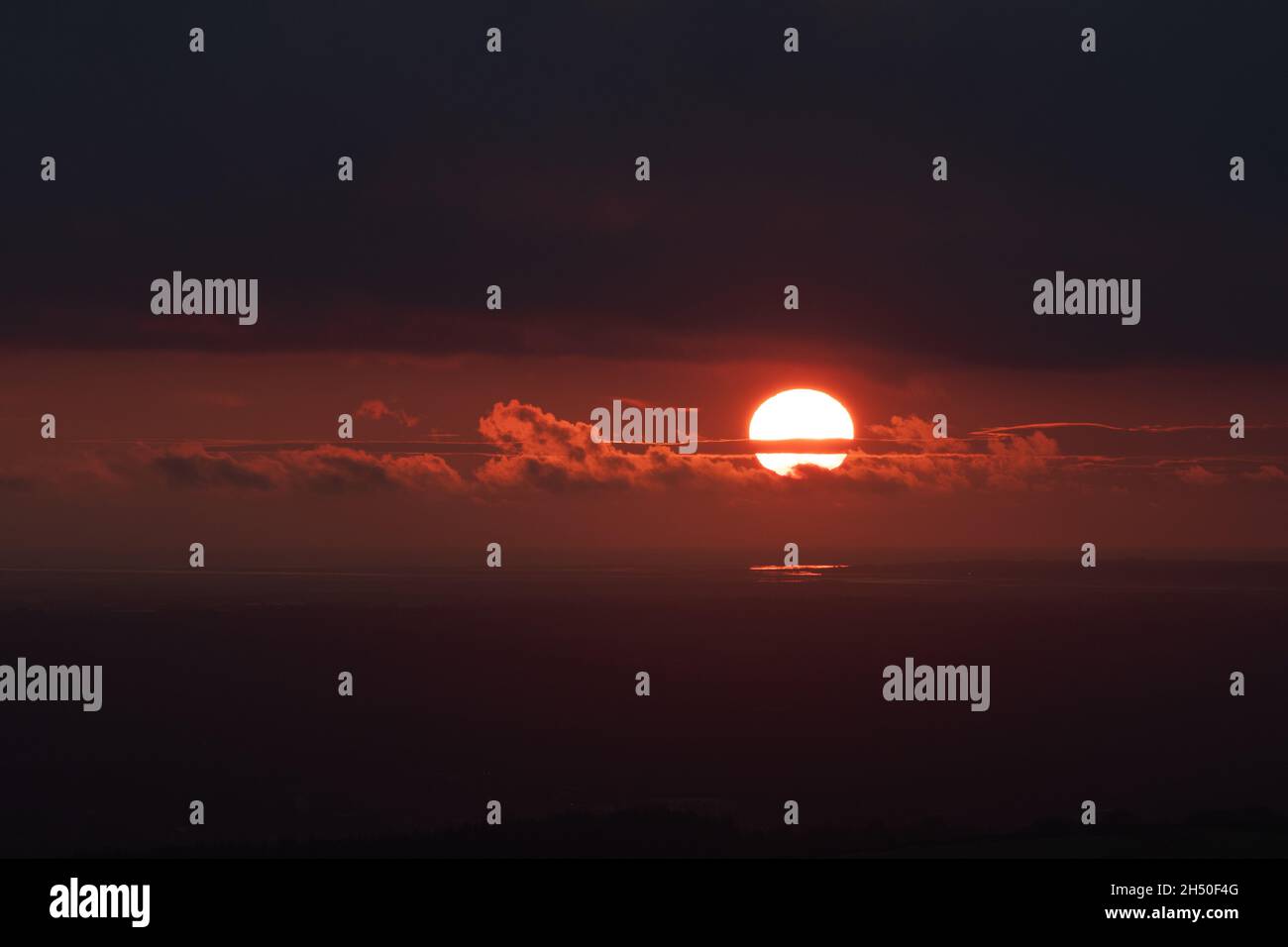 Tramonto Moody contro il cielo arancione scuro con il sole che si infrange attraverso le nuvole. Grandi aree di spazio vuoto per la copia o il testo Foto Stock