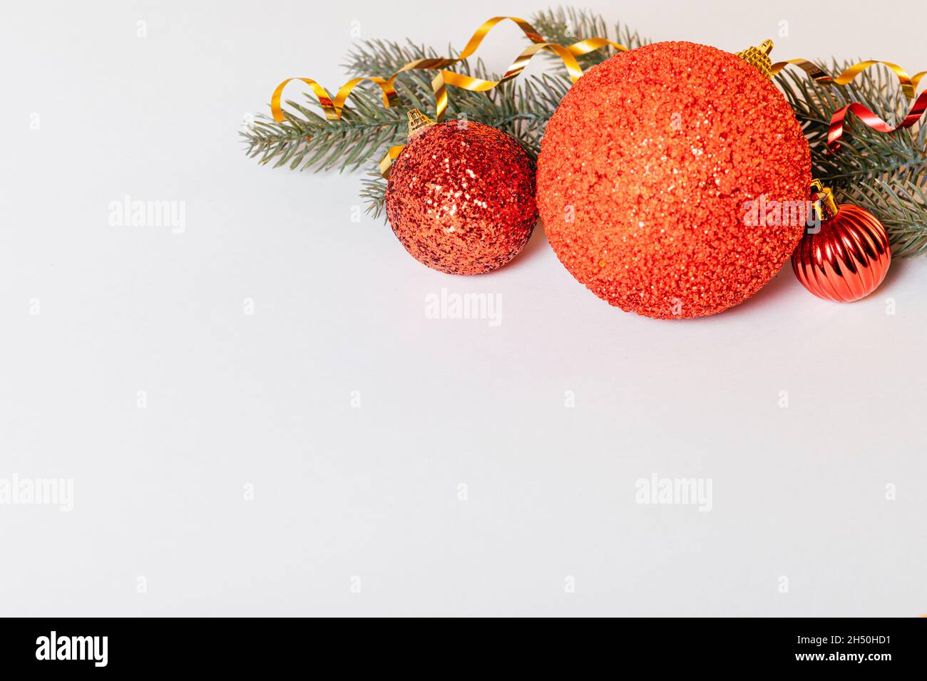 Decorazioni natalizie di palline rosse con rami di abete rosso su sfondo bianco. Spazio di copia Foto Stock