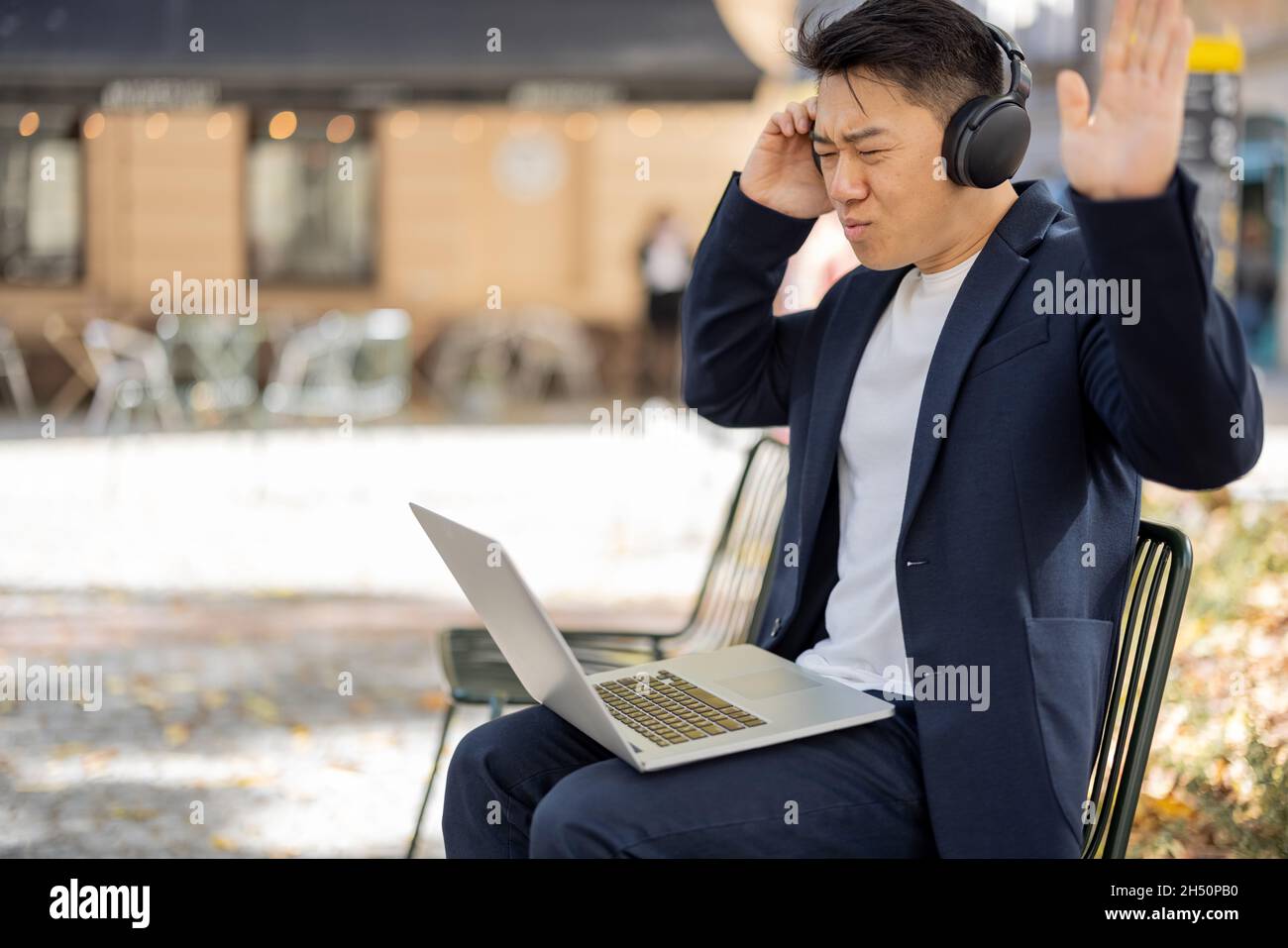 Uomo d'affari irritato che lavora su un notebook all'aperto Foto Stock