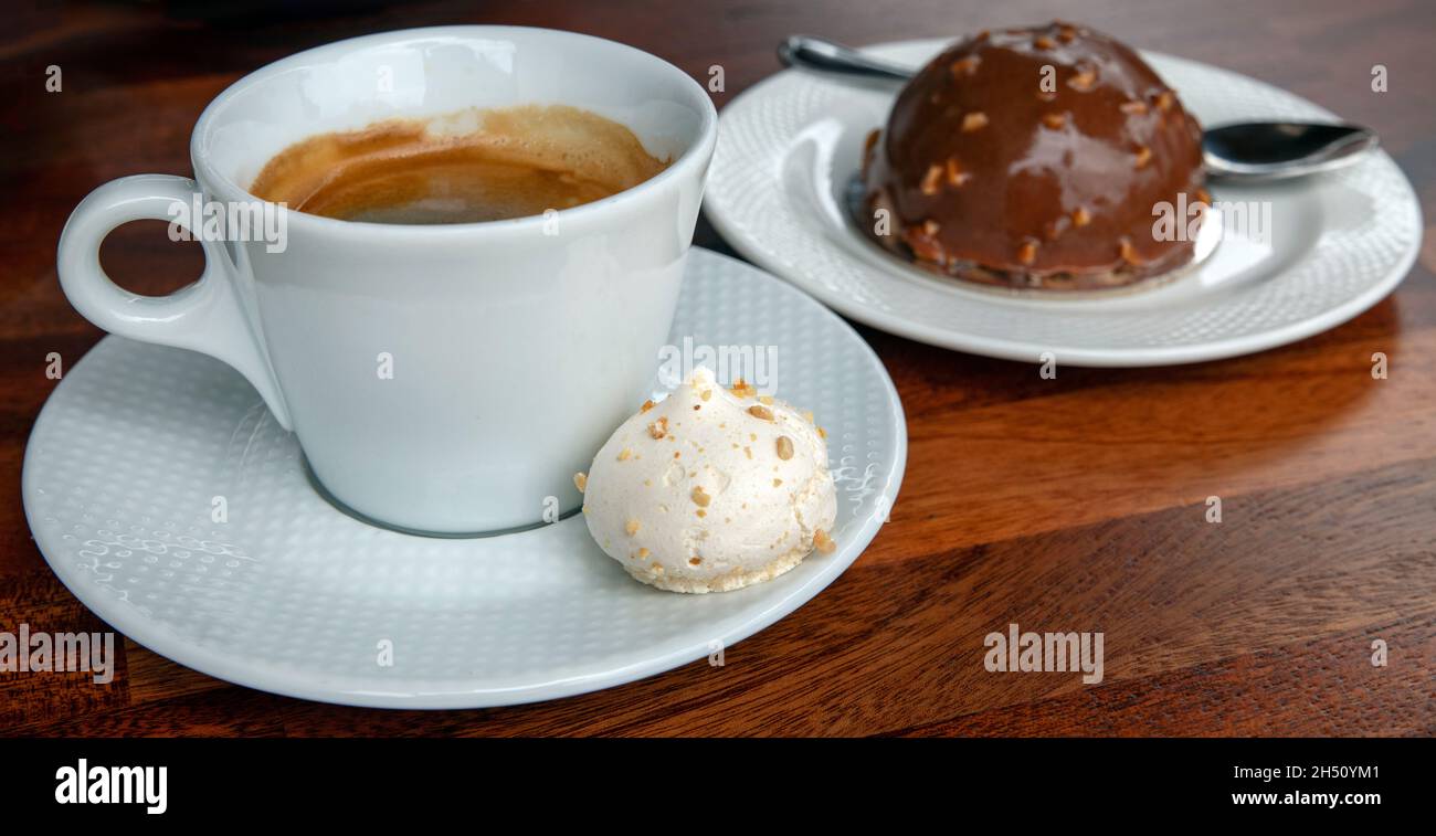 Delizioso caffe americano con una meringa dolce a parte e una piccola torta a cupola al cioccolato e noci, rituale pomeridiano con la famiglia e gli amici Foto Stock