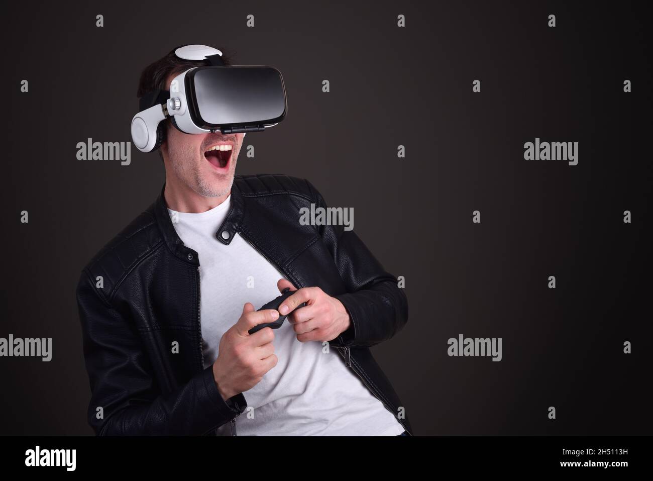 Uomo che ha vestito divertente casual giocare con occhiali di realtà virtuale con sfondo nero isolato Foto Stock