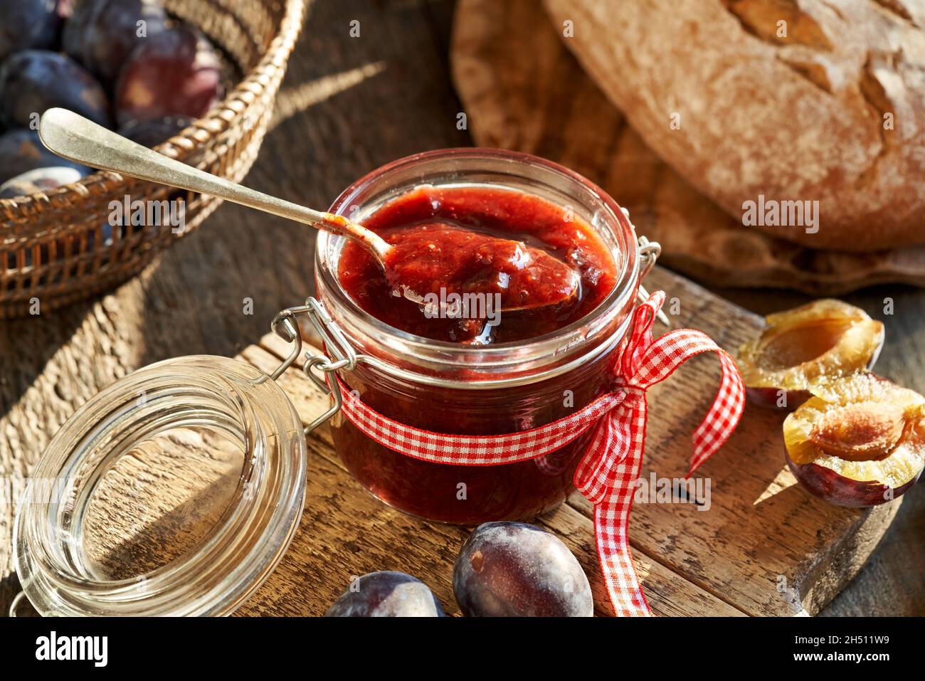 Klevela - conserve fatte in casa simili al burro di susina o alla marmellata, con un cucchiaio e pane sullo sfondo Foto Stock