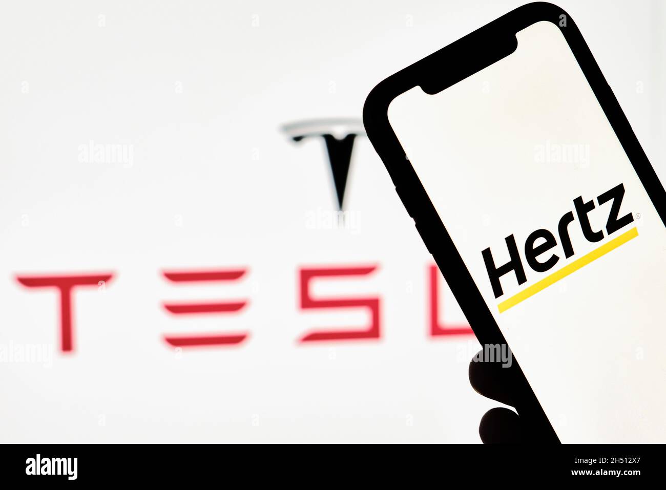 Tashkent, Uzbekistan - 29 ottobre 2021: Una persona possiede uno smartphone  con marchio Hertz sullo sfondo del logo Tesla. Ordine Hertz per Tesla  Electric Foto stock - Alamy