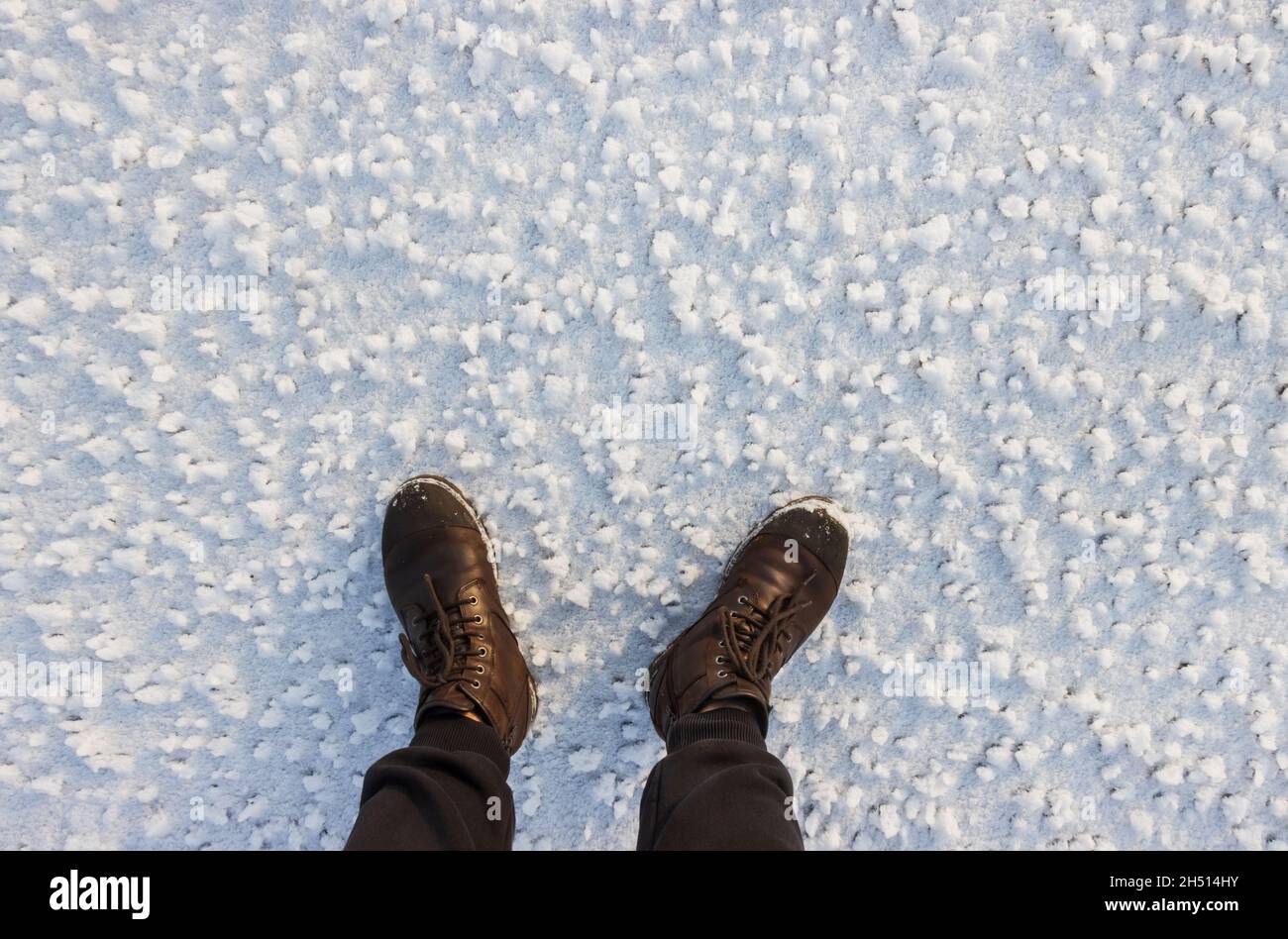 piedi maschi in stivali tra neve bianca Foto Stock