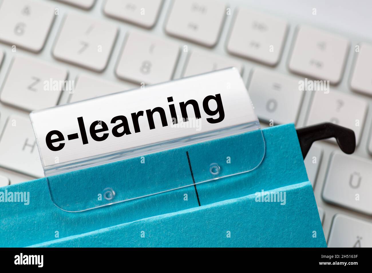 l'e-learning è riportato su un'etichetta di un file sospeso blu. In background una tastiera del computer Foto Stock