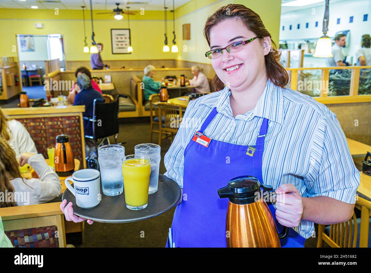 Florida Port Charlotte IHOP interno, ristorante donna donna cameriera server che serve vassoio di lavoro Foto Stock