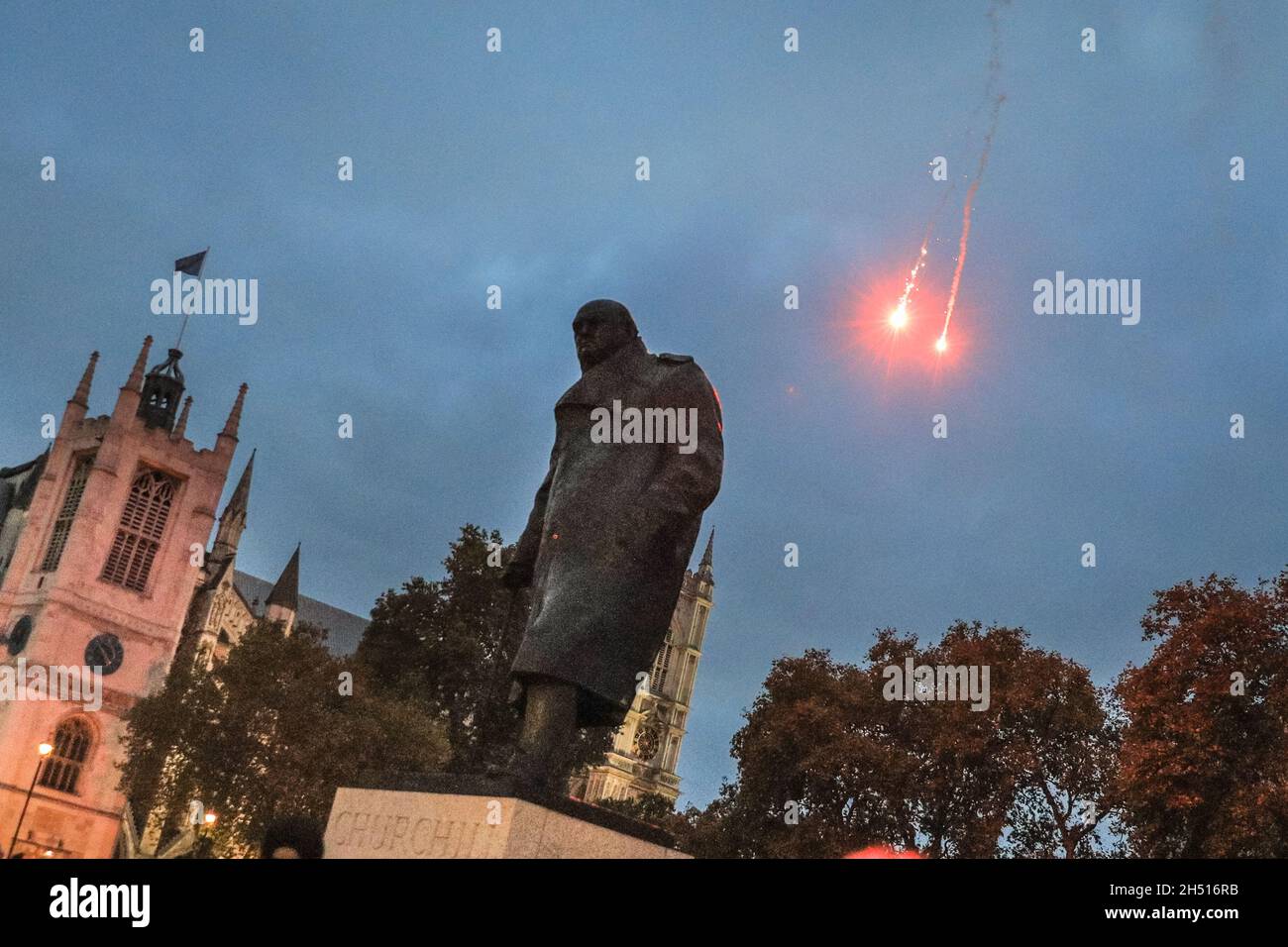 Westminster, Londra, Regno Unito. 5 novembre 2021. I fuochi d'artificio saliscono dietro la statua di Winston Churchill. I manifestanti dell'annuale Million Mask March si mescolano con i manifestanti anti anti-Lockdown e anti-vaccinazione, alcuni anche nelle maschere Guy Fawkes, in Piazza del Parlamento a Westminster questo pomeriggio e sera. Le razzi e alcuni fuochi d'artificio sono illuminati, inducendo la polizia a prendere una posizione prudente con una forte presenza della polizia in tutta Westminster stasera. Credit: Imagplotter/Alamy Live News Foto Stock