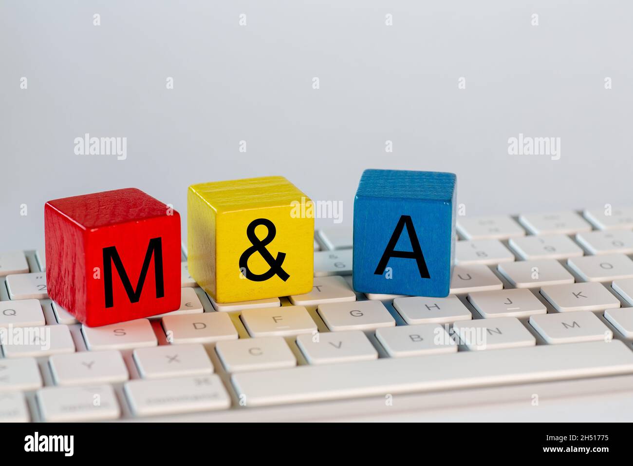 Blocchi colorati con le lettere M&B che stanno per fusioni e acquisizioni. I blocchi sono su una tastiera di computer luminosa e isolato con bianco ba Foto Stock